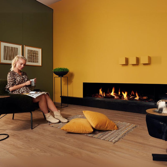 Element4 Summum 190 C with Real Flame Burner with True-to-Nature Wood Logs, Black Painted Steel Interior with Clean Face Design installed at the Guess room with a lady reading books while drinking coffee