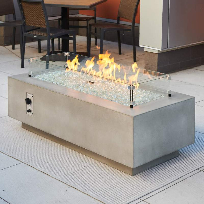 Natural Grey Cove 54 Linear Gas Fire Pit Table Installed with Clear Tempered Fire Glass Gems Burner On plus Glass Wind Guard