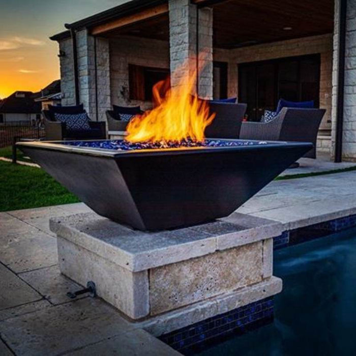 The Malibu Square Fire Bowl in Black Concrete Placed at the Poolside with Cerulean Pebbles with Bullet Burner On plus Match Lit Ignition System