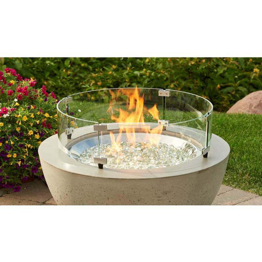 The Outdoor Greatroom 20 Round Glass Wind Guard installed on Cove Round Gas Fire Pit Bowl plus Fire Burner On with Clear Tempered Fire Glass Gems