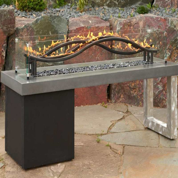 The Outdoor Greatroom 56 Black Wave Gas Fire Pit Burner with Black Tempered Fire Glass Gems plus Fire Burner On with Glass Wind Guard Full View