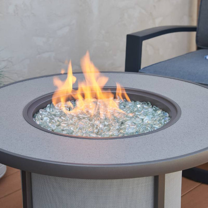 The Outdoor Greatroom Grey Stonefire Round Gas Fire Pit Table  Installed at Deck with Clear Tempered Fire Glass Gems plus Fire Burner On Scaled