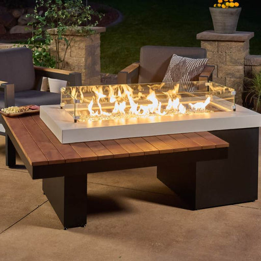 The Outdoor Greatroom Iroko Uptown Linear Gas Fire Pit Table Installed at Terrace with Clear Tempered Fire Glass Gems plus Fire Burner On and Glass Wind Guard Installed
