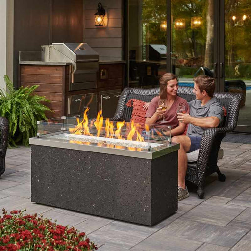 The Outdoor Greatroom Stainless Steel Key Largo Linear Gas Fire Pit Table Placed at the Deck Family with Clear Tempered Fire Glass Gems plus Fire Burner On and Glass Wind Guard V1