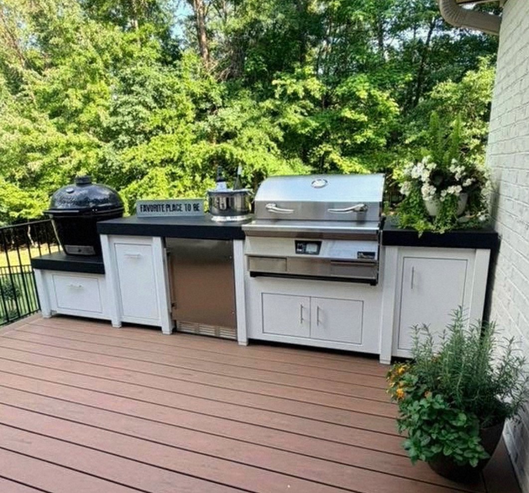 Outdoor kitchen installation on a backyard deck: matte-black cabinetry with integrated grill and side burners, sized to the deck footprint.